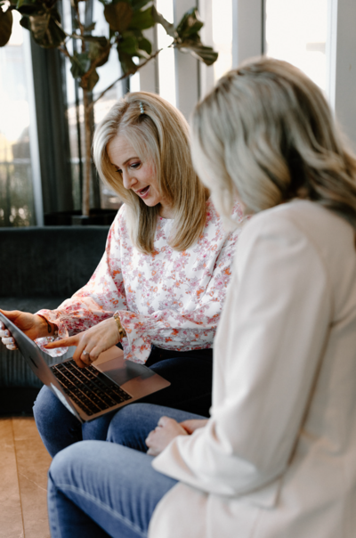 Online nutrition coach for perimenopause moms, Ashley Malik, using laptop with client at coffee shop