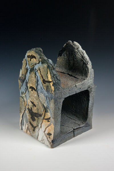 A cinder block that was hand made out of clay is decorated with underglaze to resemble graffiti and various other imagery