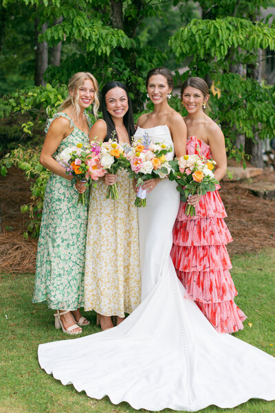 girls in dresses holding flower bouquets and smiling at camera
