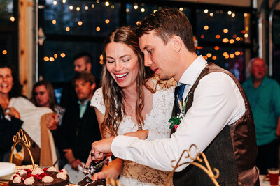 Bride and groom cutting cake at wedding reception at Izaak Walton Inn in Essex, MT