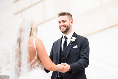 A close up image of grooms face as he sees his bride and takes her hands in his for the first time on the steps of the Detroit Institute of Art