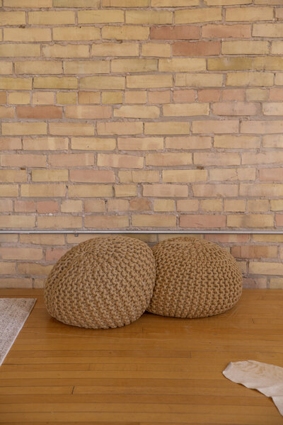 Two jute pouf pillows on hardwood floor.