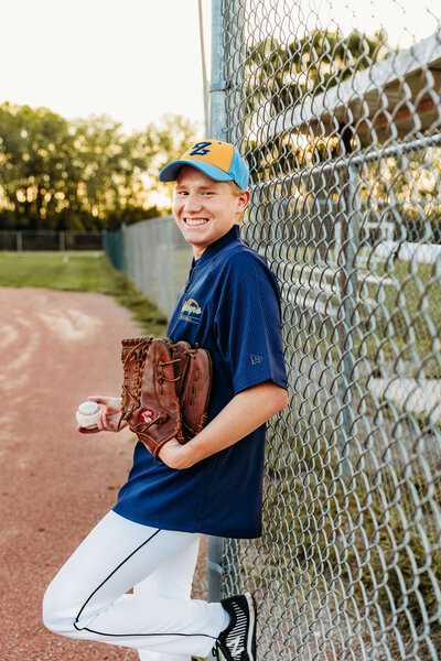 baseball player holding glove by his face for his senior photography session