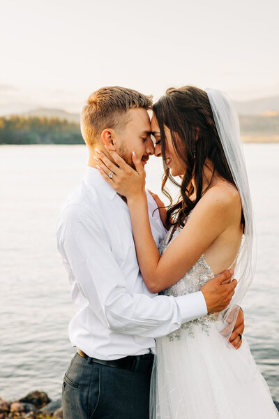 Bride and groom embracing on shore of Flathead Lake at Flathead Lake Forevers in Big Arm, MT