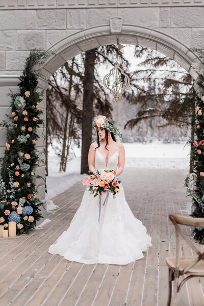 A bride posing under the archway at archway manor in the winter