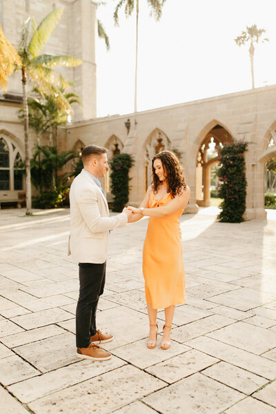 engaged couple holding hands in the courtyard of Bethesda-by-the-sea church