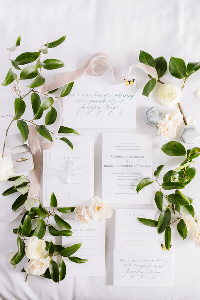 Wedding invitation suite flat lay decorated with greenery