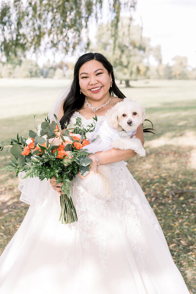 Bride smiling with a dog in her arms