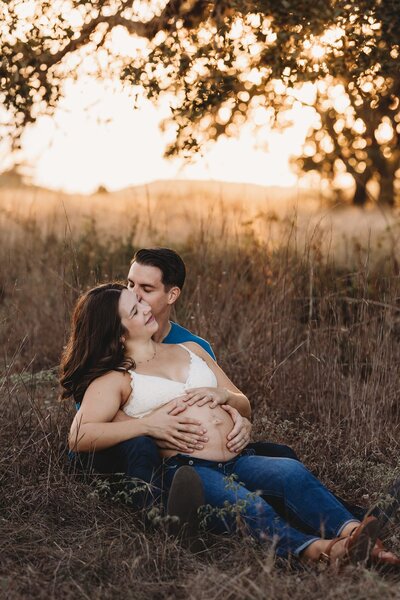 Pregnant woman and husband sitting on the grass
