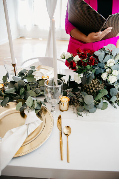 wedding planner holds a folder in front of wedding reception table