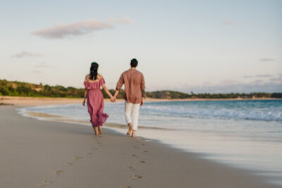 couple walking on beach with footprints in the sand