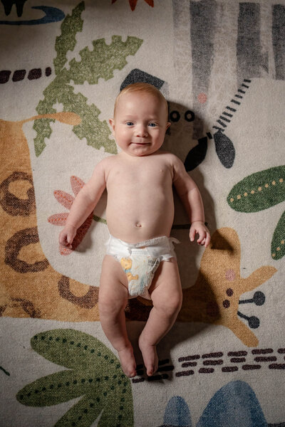 One month old baby in diaper laying on jungle rug in Boston