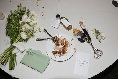 Lat night flat lay with cake, flower bouquet, cake cutting utensils, wedding favors during reception at Tuscan Rose Ranch in Santa Paula California 