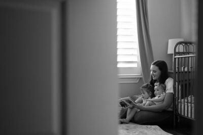 Black and white artistic photograph of a horse's head between another horse's legs