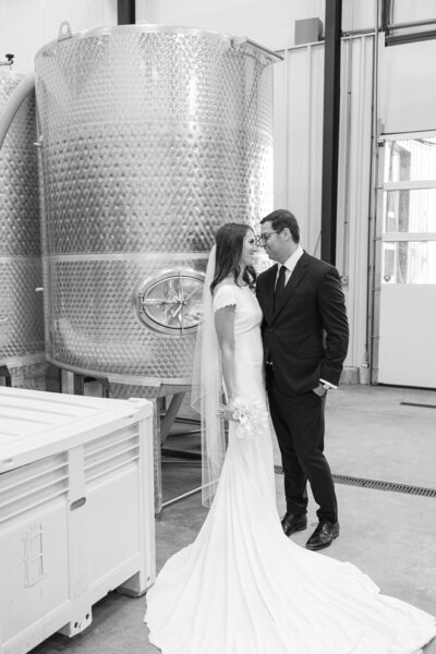 bride and groom smiling at each other in wine cellar