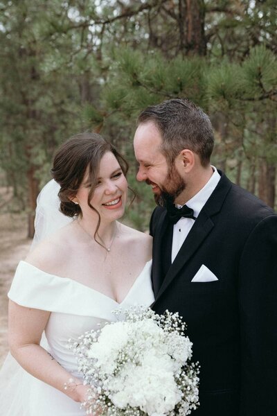 A close up of a groom looking at his bride while she smiles looking off to the side.