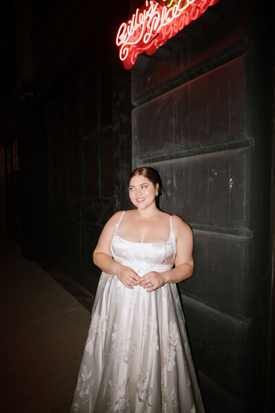 Bride standing underneath a red neon sign
