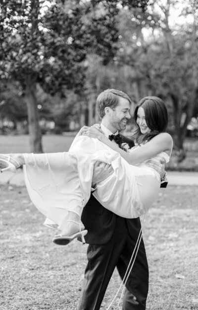 Groom holding bride in his arms in Forsyth Park, Savannah Ga.