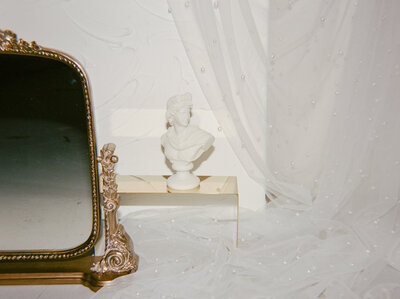 glimmering gold anthropologie mirror, sculptural ivory bust candle, details on film for florist brand photography