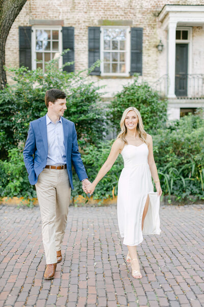 A soon to be bride and groom hold eachother's hands.