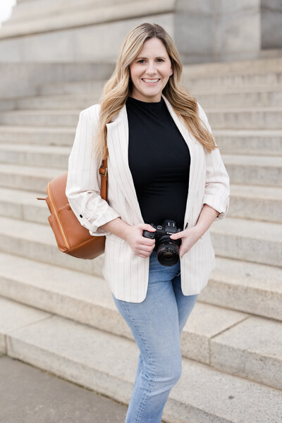 Senior Photographer Amanda is holding her camera and smiling
