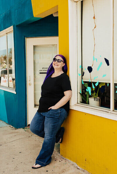 Heidi Thompson leaning against blue and yellow wall in San Diego, CA.