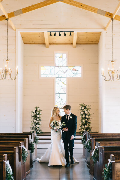Bride and groom walking down aisle in front of floral altar arrangement designed by Abby Grace Florals at Saluda SC chapel wedding