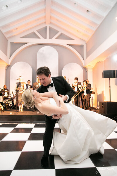 A husband dipping his wife on the dance floor during their wedding reception.
