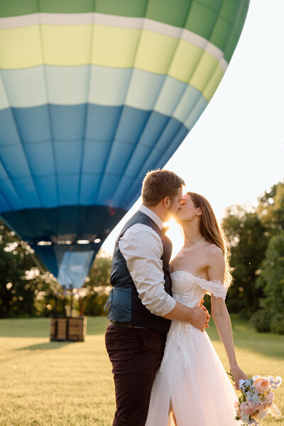 Couple embracing in front of a hot air balloon.