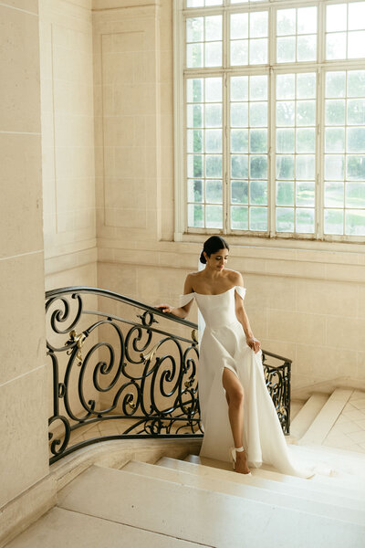A bride posing on an elegant chateau staircase.