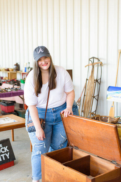 Lauren looks inside antique wooden chest at flea market