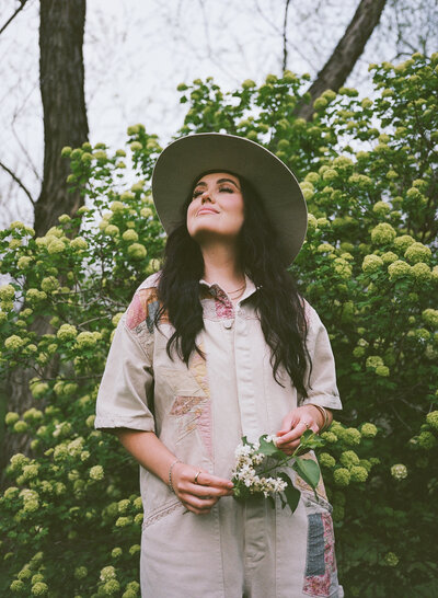 woman standing in backyard cottage garden surrounded by greenery and soft spring blooms

