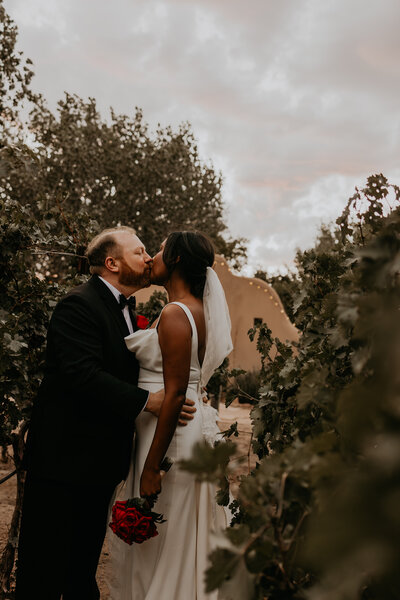 bride and groom standing in front of a lake