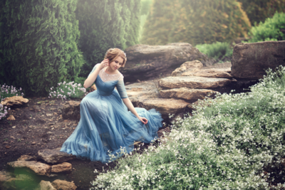 Woman in blue dress kneeling in a garden of flowers