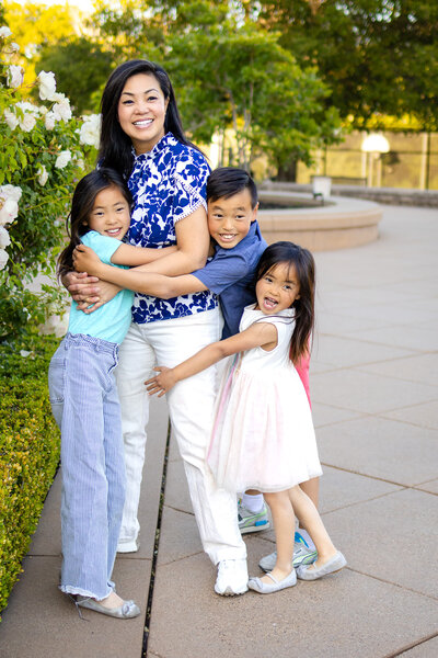 Bay Area Family Photographer A joyful mom embracing her three smiling kids during a golden hour family session – captured by ellobelle photography.