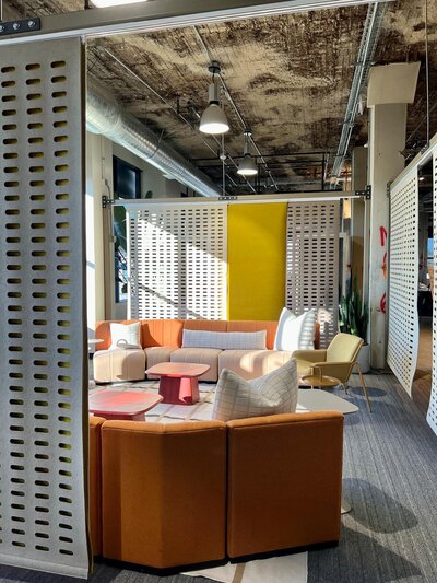Conference room with patterned white and green walls, modern pendant lighting, and comfortable seating.