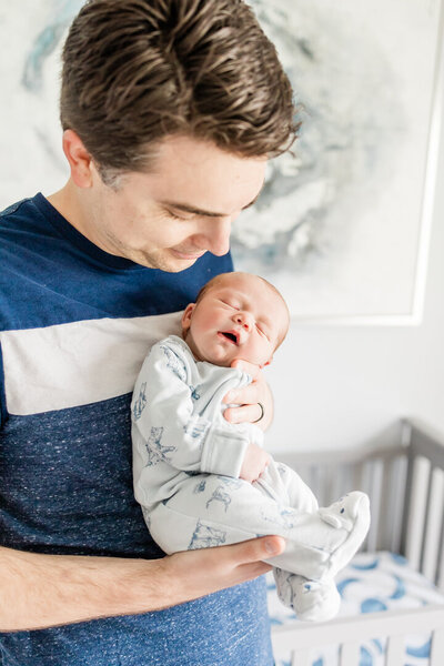 man holding newborn baby boy while he sleeps