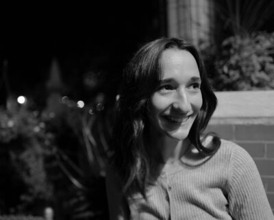 Black and white photo of woman with brown natural hair smiles off camera. 