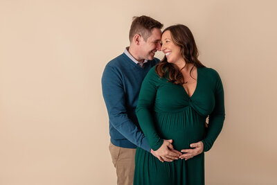 pregnant mom in green dress cuddling with dad by philadelphia maternity photographer