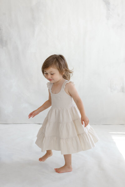 Young girl playing joyfully in a white dress, captured in a lifestyle family photography session by Little Palm Photography in Marin County.