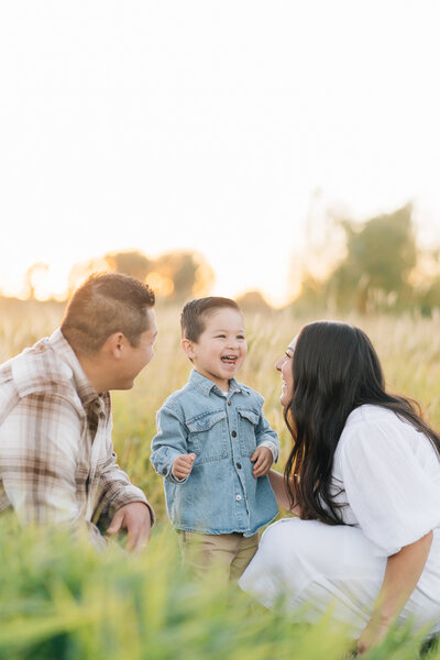 Photos taken in a field in Memphis, Tennessee by Kailee Matsumura a Memphis Family Photographer. Young mom with two toddler boys. Both children smiling at the camera.