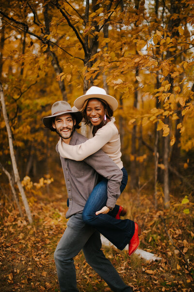 A man gives a woman a piggy back ride during their Door County Wisconsin Engagement