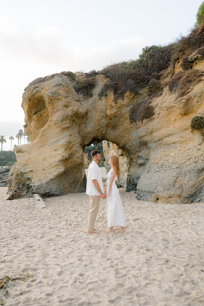 couple holding hands under a natural stone arch