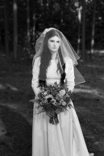 A bride standing in a field holding a bouquet of flowers