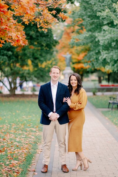 couple taking fall engagement photos on a college campus