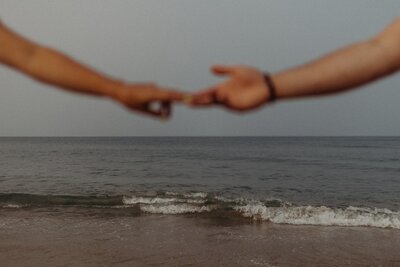 couple holding hands in front of ocean