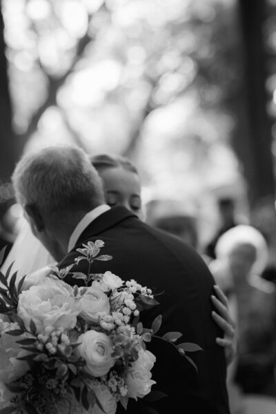 Timeless black and white photograph of a bride and her father hugging captured by Texas documentary film wedding photographer.
