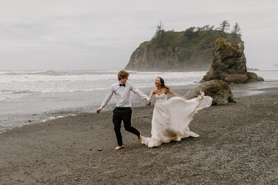 Couple runs along the Washington coast during their PNW Elopement.