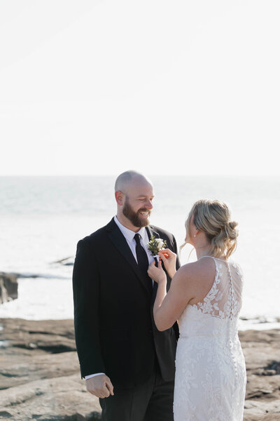A person putting a boutonniere on their partner's jacket 