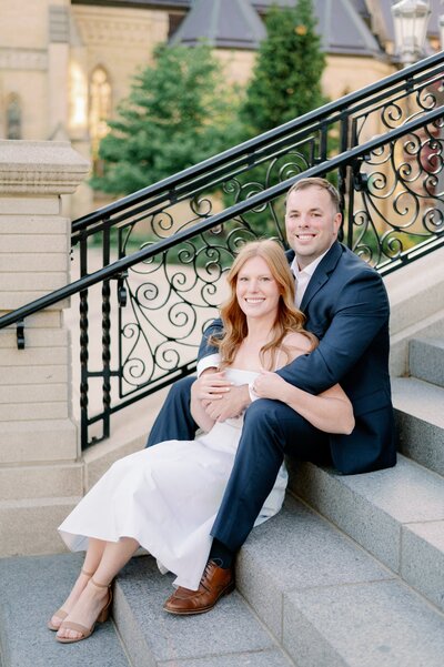 man and woman posing for engagement photos on the steps of a building at Notre Dame